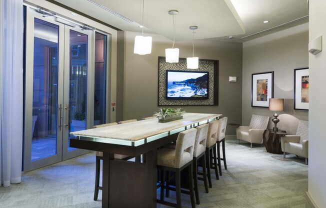 A dining space with an 8-person dining table, a seating area with armchairs, and a wall-mounted HDTV