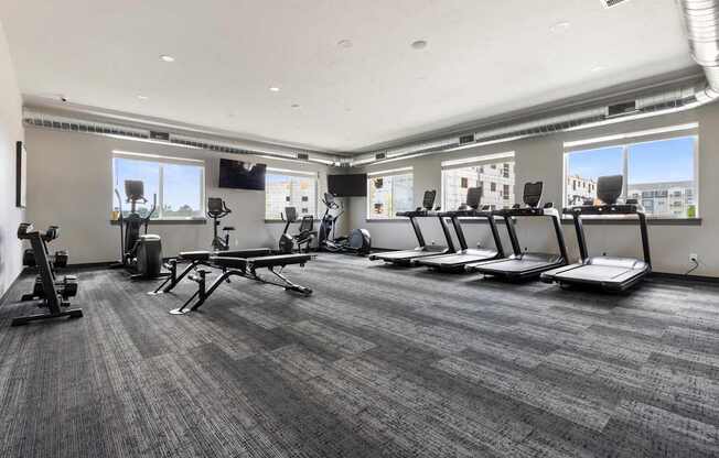 A gym with treadmills, elliptical machines, and a bench.