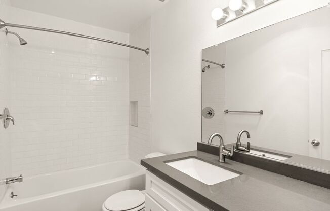 A white bathroom with a toilet, sink, and bathtub.