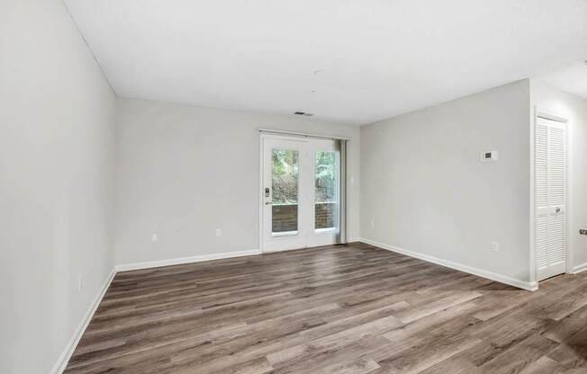 A room with wooden flooring and a sliding glass door.