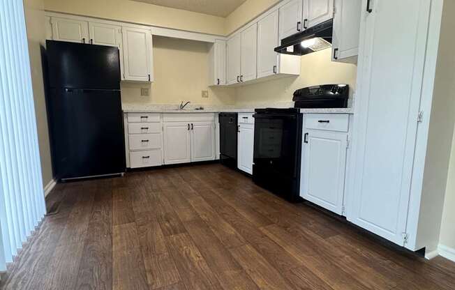 A kitchen with black appliances and white cabinets.