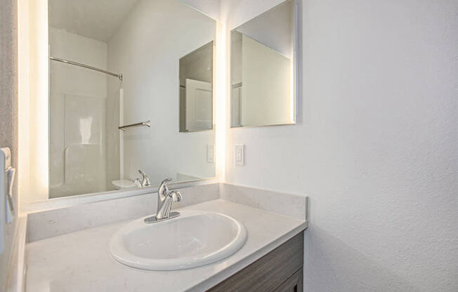 A bathroom with a white sink and a mirror above it at Meadowbrooke Apartment Homes in Kentwood, MI 49512