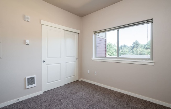 a bedroom with a large window and carpet