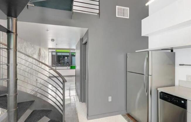 a kitchen with a stainless steel refrigerator next to a spiral staircase