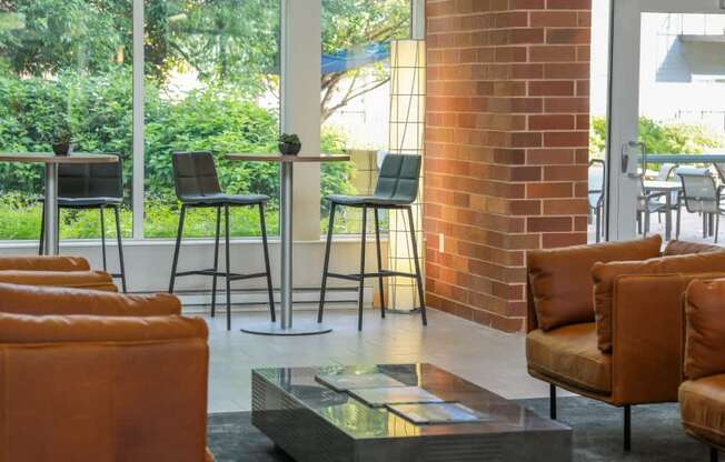 A room with a glass table and leather chairs.