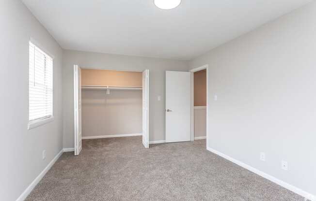 an empty room with a closet and a window