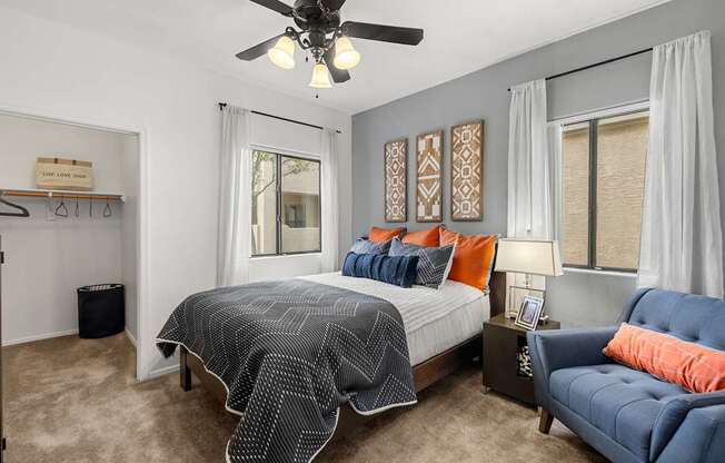 A bedroom with a bed, a couch, and a ceiling fan.