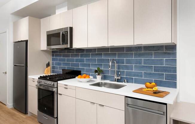 a kitchen with white cabinets and a blue subway tile