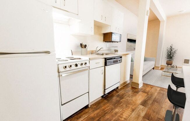 a kitchen with white appliances and a wood floor