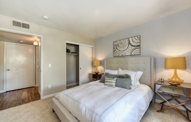 Bedroom with Large Extended Closet, Carpet, Lamps and Abstract Painting Above Bed