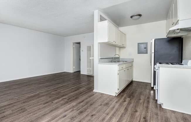 an empty kitchen and living room with a hard wood floor