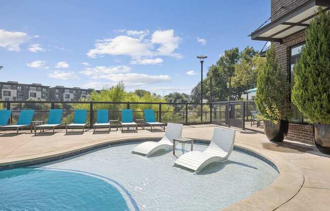 A pool with blue water and white chairs.