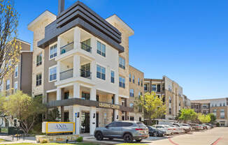 A modern apartment building with a leasing sign in front.