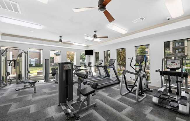 A gym with a variety of equipment including a treadmill, weights, and a stationary bike.