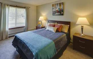 Bedroom, wall art, green and purple bedspread, and lamps