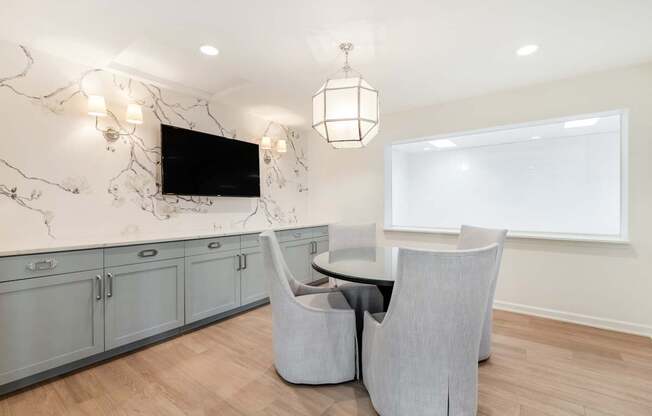 A modern living room with a television, grey armchairs, and a marble backsplash.