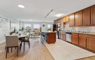 A modern kitchen with wooden cabinets and a dining table.