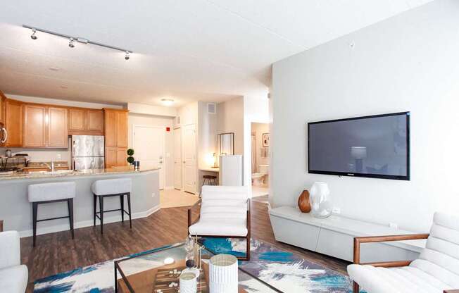 A modern living room with a white couch and a television on the wall.
