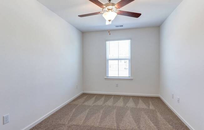 an empty room with a ceiling fan and a window
