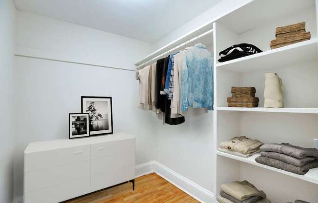 A white closet with clothes and towels on shelves.