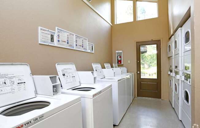 A laundromat with washers and dryers lined up.