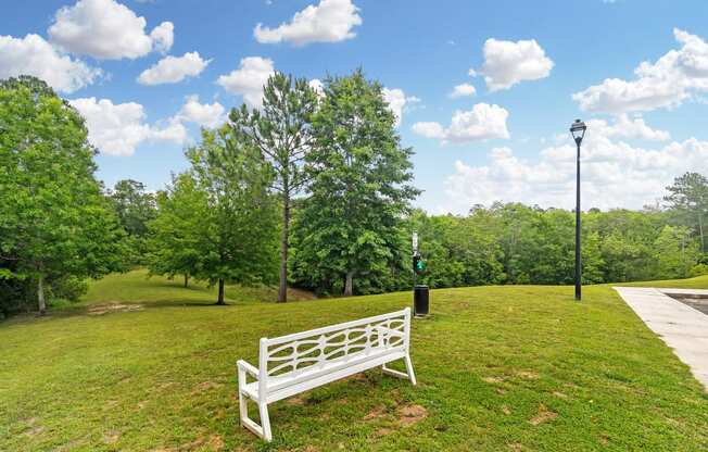 a park bench sitting in the grass next to a sidewalk