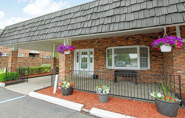 the front of a brick building with a porch and flowers in pots