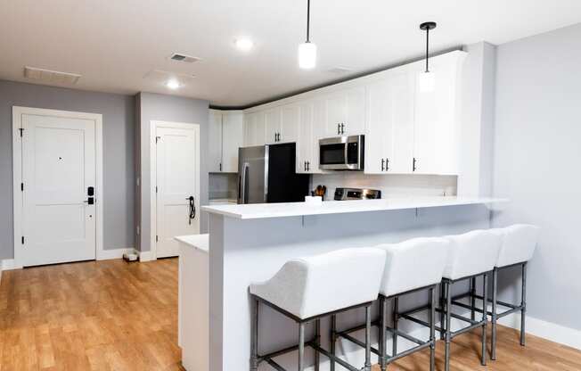 a kitchen with white cabinets and a white counter top with three stools in front of it