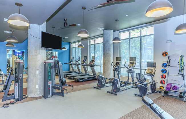 a gym with treadmills and other exercise equipment and windows