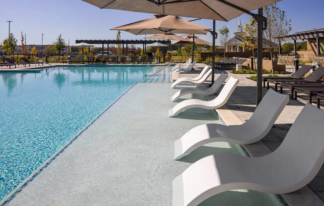 A pool with a row of chairs and umbrellas.