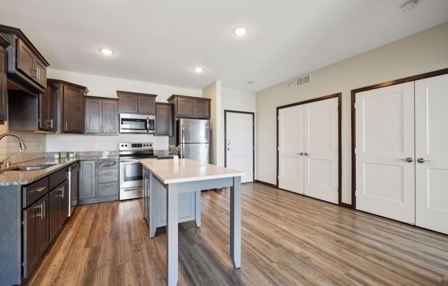 an open kitchen with wood flooring and stainless steel appliances