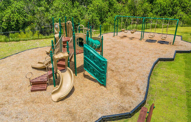 A playground with a green fence and a yellow slide at Mode at Melbourne, LLC Apartments, Florida, 32901