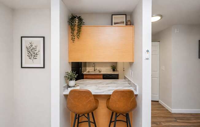 A kitchen with a table and two chairs.