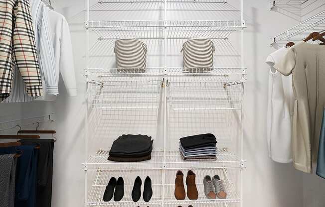 A white closet with clothes and shoes organized on shelves.