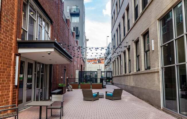 a courtyard with chairs and tables in front of a brick building