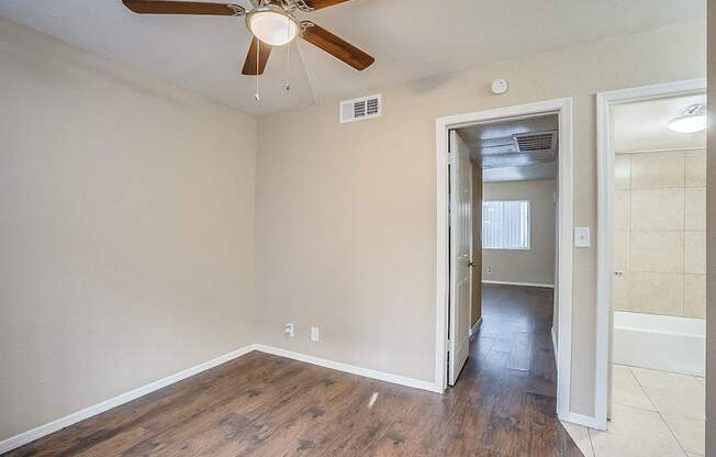 A room with a ceiling fan and a doorway leading to another room.