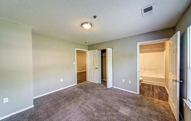 an empty living room with a door to a bathroom and a closet