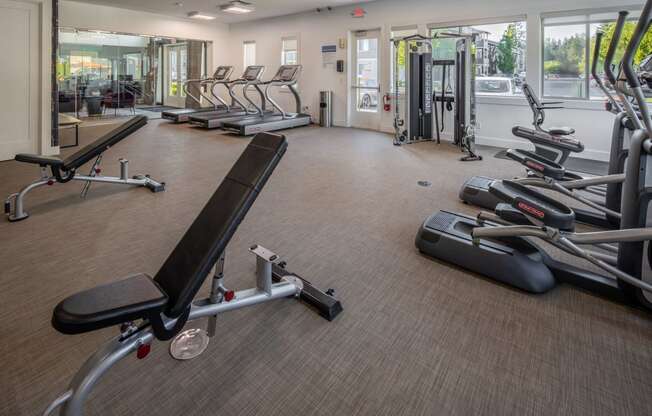 a gym with cardio equipment on the floor and glass windows