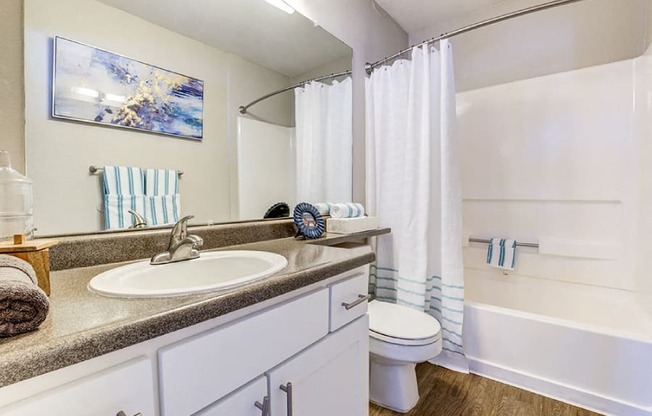 A bathroom with a white tub, sink, and toilet.