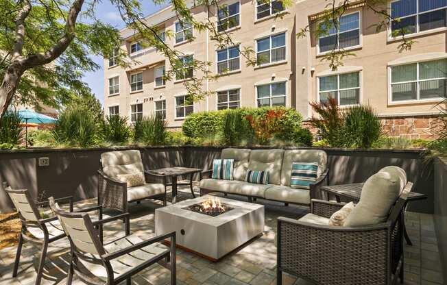 a patio with furniture and a fire pit in front of an apartment building