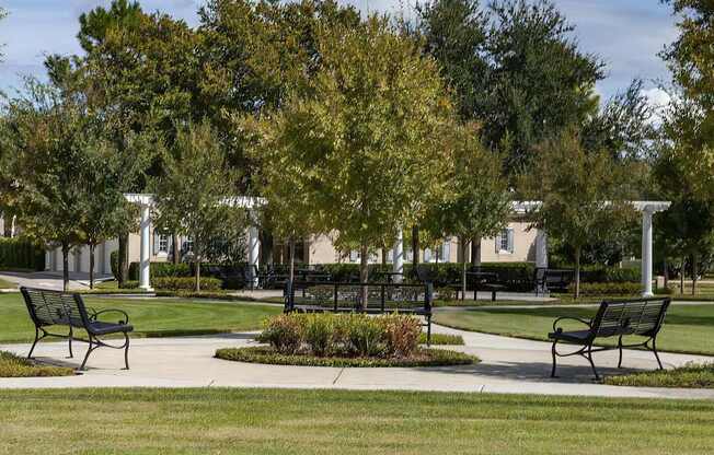 A park with benches and trees in the foreground and a building in the background.