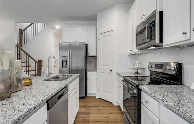 a kitchen with granite counter tops and a stainless steel refrigerator