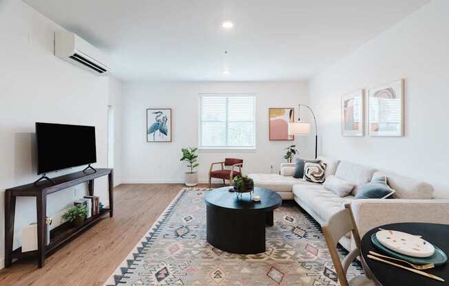 A living room with a white couch, a black coffee table, and a rug with a pattern.