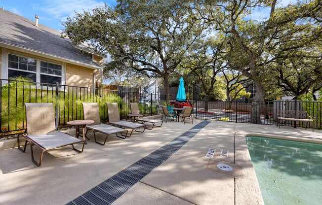 A pool area with a hot tub and lounge chairs.