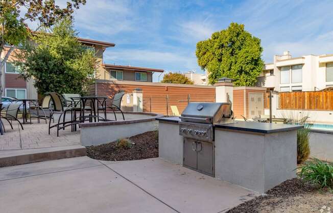 a backyard with a barbecue grill and a patio with tables and chairs