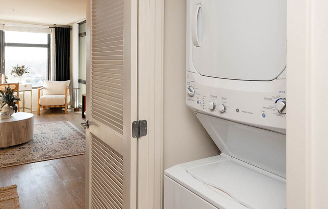 A white dryer is sitting in a room with a round table and chairs.