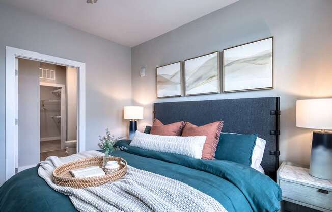 A bedroom with a bed, nightstand, and a painting on the wall.