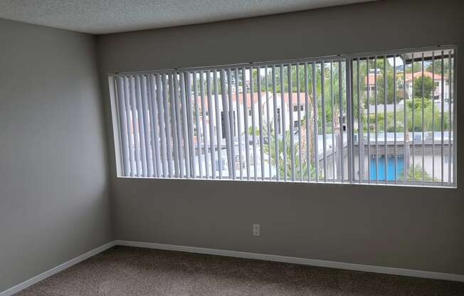 Carpeted bedroom with fantastic window and walk-in closet at La Mesa Village Apartments in La Mesa, California.