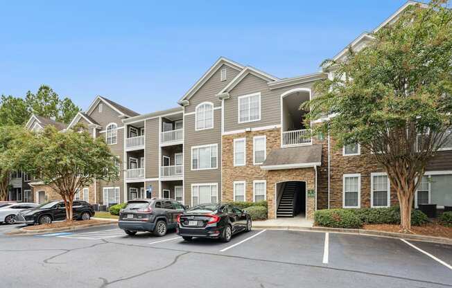 A parking lot in front of a building with cars parked.