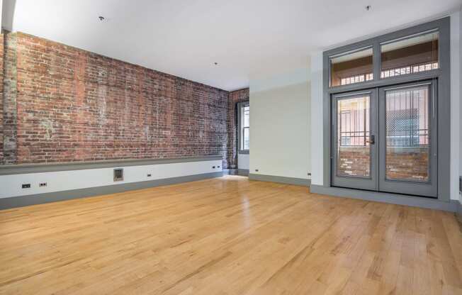 an empty living room with a brick wall and a glass door